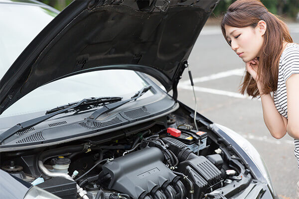 車のエンジンが故障して困っている女性